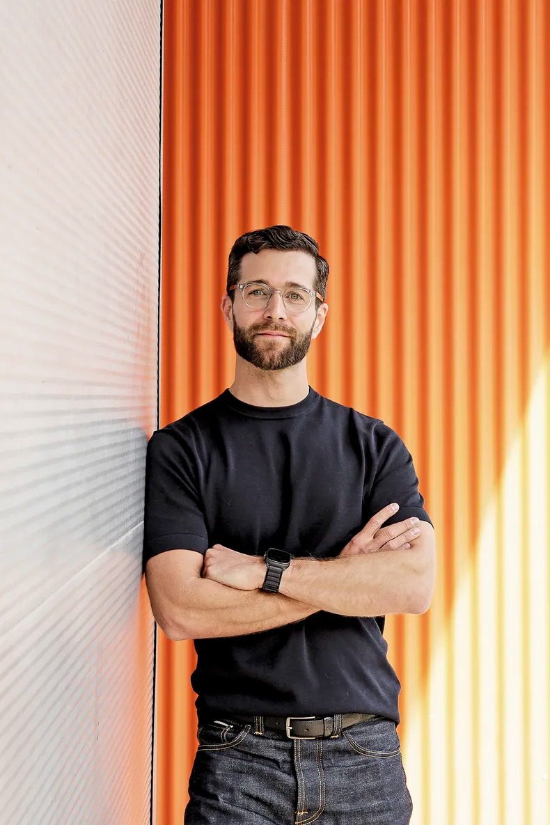 Jorge Milburn, leaning against an orange wall